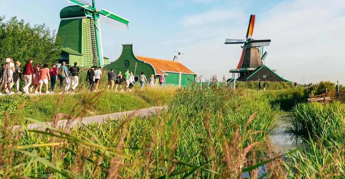 Tarred timber windmills with green trim lining the Zaan river at Zaanse Schans, the main stop on Amsterdam windmill tours in North Holland